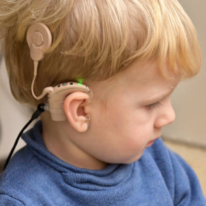 A boy with a Cochlear Implant and hearing aid. 